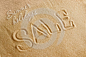 The word sale is painted on the sand and the inscription is a summer holiday. Beach background. View from above. The concept of