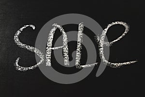 The word sale written in white chalk on a black chalkboard