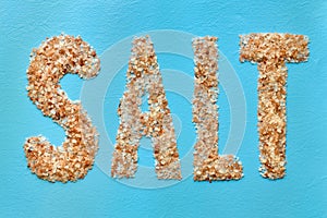 Word Salt is made of coarse Himalayan pink salt on blue background