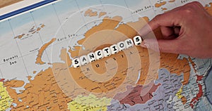 Word Sanction constructed from white cubes lies on Russia map