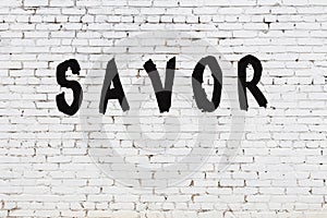 Word savor painted on white brick wall