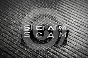 Word Scam of black cubes on a gray.