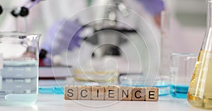 Word science is collected with wooden cubes on laboratory table.