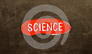 The word SCIENCE written in red on a black and white background near the pen