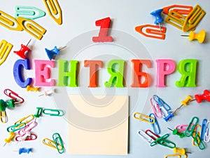 Word September 1 in Russian on a white sheet of paper with paper clips and pins. Back to School concept