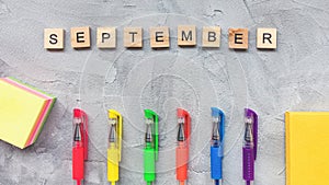 Word SEPTEMBER and multicolored gel pens on a gray background