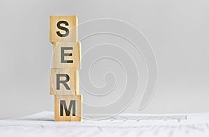 word SERM with wood building blocks, light gray background. document with numbers on background, business concept. space