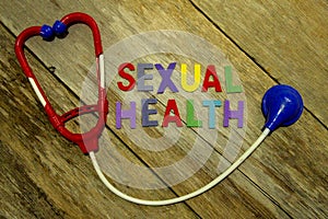 Word SEXUAL HEALTH colorful wooden alphabet letters set and toy stethoscope on wooden background. Healthcare and medical concept