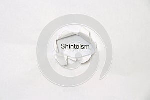 Word Shintoism on white isolated background through the wound hole in the paper.