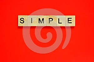Word simple. Top view of wooden blocks with letters on red surface