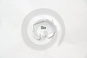 Word Six on white isolated background through the wound hole in the paper photo