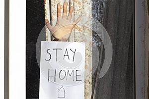 Word slogan and hand on window glass. Stay home and isolate yourself watchword. Quarantine spring 2020, coronavirus covid-19. City photo