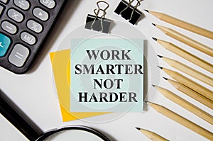 word smarter not harder written on yellow sticker and white background near office supplies. word