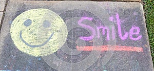 The word Smile" and smiley face emoji sidewalk chalk