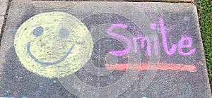 The word Smile" and smiley face emoji sidewalk chalk photo