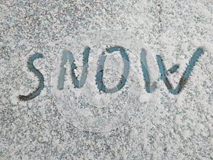 Word snow is written in the snow on an old painted surface