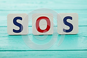 Word sos on blue wooden background. Copy space. Macro letters. Selective focus.