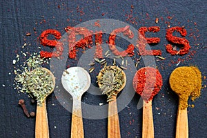 The word spice is written on a black background. Various spices ground turmeric pepper ginger cinnamon herb seasoning salt paprika