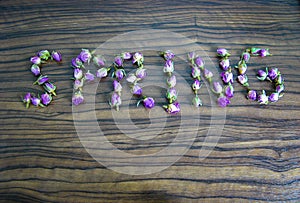 The word spring is made of dried flower buds on wooden background.