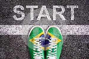 Word Start written on an asphalt road with legs and shoes colored with brazilian flag