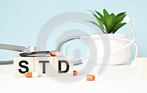 The word std is written on wooden cubes near a stethoscope on a wooden background. Medical concept