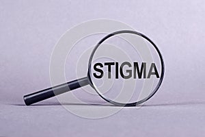 The word STIGMA is written on a magnifying glass on a light violrt background
