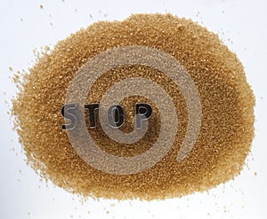 word stop made from metal letters. pile of cane brown sugar isolated on white background