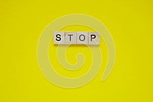 Word stop. Top view of wooden blocks with letters on yellow surface