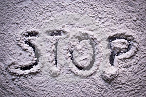 Word Stop written in white flour powder. Concepts of drug abuse as people turn to narcotics abuse during the hard times of covid