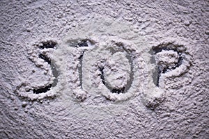 Word Stop written in white flour powder. Concepts of drug abuse as people turn to narcotics abuse during the hard times of covid