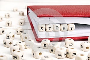 Word Story written in wooden blocks in red notebook on white woo