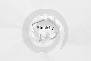 Word stupidity on white isolated background through the wound hole in the paper