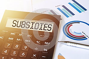 Word SUBSIDIES on calculator. Business and finance concept