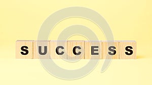 Word success with small wooden blocks on yellow background