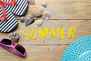 The word summer made of paper yellow letters and summer, beach accessories on a natural wooden background. summer. vacation. relax