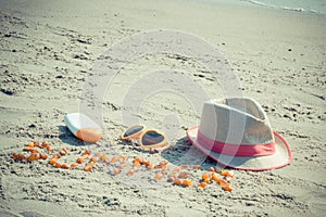 Word summer, sunglasses, sun lotion and straw hat on sand at beach. Summer time