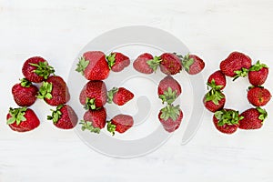 The word `Summer` written in russian with fresh strawberries.  Close up