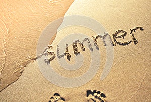 The word summer written on sand.