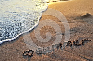 The word summer written on sand.