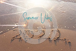 The word summer 2022 written in sea sand. Warm sunset time, vacation and enjoyment