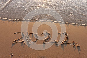 The word summer 2022 written in sea sand. Warm sunset time, vacation and enjoyment