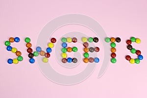The word sweets are contained by colored candies on a pink background