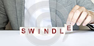 Word SWINDLE made with wood building blocks photo