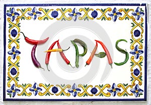 word TAPAS from red, green, yellow, purple chili pepper, vegetable letter, board with blue, yellow, green flower, green leaf