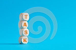 The word task on tiered wooden cubes on blue background. Task accomplishment