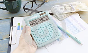 Word Tax 2022 on the calculator. Business and tax concept .Calculator, currency, book, tax form, and pen on wooden table.