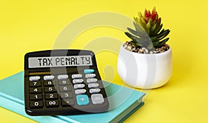 The word TAX PENALTY on a calculator. Finance concept on yellow background