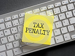 The word tax penalty written on a sticky note paper on computer keyboard