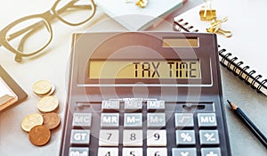 Word Tax time on the calculator. Business and tax concept .Calculator, currency, book, tax form, and pen on table.Top view