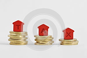 The word Tax written with miniature houses on top of coins - Home taxes decrease concept